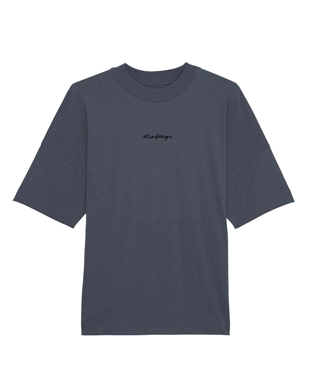 A person wearing a oversized unisex drop shoulder t-shirt in gray color, with a high neck and long sleeves, standing in a public area.