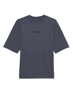 A person wearing a oversized unisex drop shoulder t-shirt in gray color, with a high neck and long sleeves, standing in a public area.